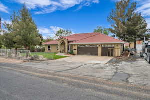 Mediterranean / spanish home featuring fence, an attached garage, stucco siding, a tile roof, and concrete driveway