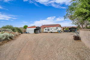 View of yard with fence, a storage shed, an outdoor structure, driveway, and a carport