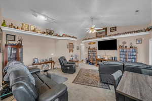 Carpeted living room featuring visible vents, ceiling fan, and vaulted ceiling