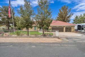 View of front facade featuring a tile roof, concrete driveway, a garage, stucco siding, and a fenced front yard