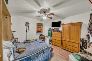 Bedroom featuring light wood finished floors, a textured ceiling, and a ceiling fan