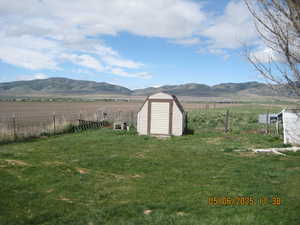 View of yard featuring fence, a storage shed, and a mountain view