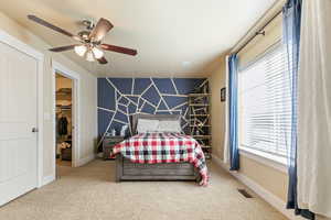 Carpeted bedroom featuring ceiling fan, a spacious closet, visible vents, and multiple windows