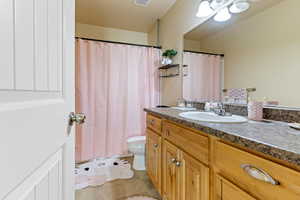 Bathroom featuring toilet, curtained shower, visible vents, tile patterned flooring, and vanity