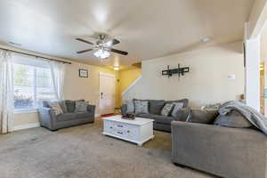 Carpeted living room featuring visible vents, baseboards, and ceiling fan