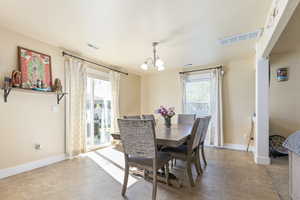 Dining area with a chandelier, a wealth of natural light, and visible vents