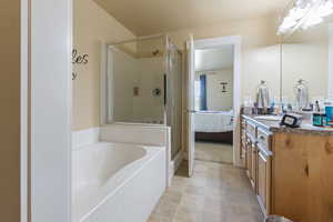 Full bath featuring connected bathroom, tile patterned floors, a bath, a shower stall, and vanity