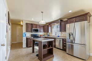 Kitchen featuring a sink, open shelves, dark brown cabinetry, light countertops, and appliances with stainless steel finishes