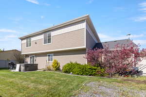 Rear view of house featuring a hot tub and a yard