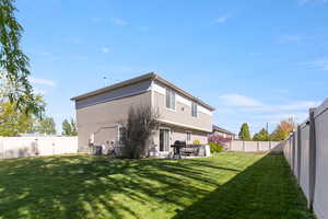 Back of house featuring central AC unit, a yard, and a fenced backyard