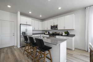 Kitchen with stainless steel appliances, light wood-style flooring, a kitchen breakfast bar, and a sink