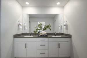 Full bath with a textured ceiling, recessed lighting, double vanity, and a sink