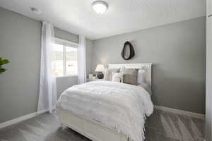 Bedroom with carpet, a textured ceiling, and baseboards