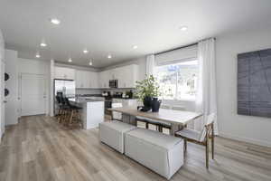 Dining room featuring light wood finished floors, a textured ceiling, baseboards, and recessed lighting