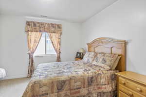Carpeted bedroom with baseboards, lofted ceiling, and visible vents