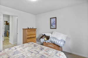 Carpeted bedroom featuring freestanding refrigerator, a textured ceiling, and baseboards