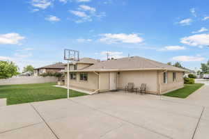 Rear view of house featuring a lawn, a patio area, stucco siding, and roof with shingles