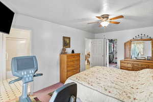 Bedroom with a closet, a textured ceiling, ceiling fan, a spacious closet, and baseboards