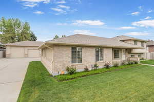 Split level home with a front lawn, a shingled roof, fence, and a detached garage