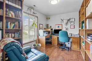 Office space with light wood-style floors, visible vents, and a textured ceiling