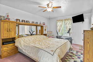 Bedroom with a textured ceiling, ceiling fan, and carpet