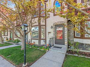 Entrance to property featuring stone siding, stucco siding, and a lawn