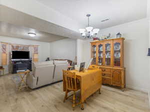Dining space with an inviting chandelier, a textured ceiling, visible vents, and light wood-style floors