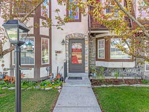 View of exterior entry featuring stone siding, stucco siding, and a yard