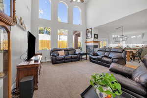 Living room with carpet flooring, plenty of natural light, a fireplace, and a towering ceiling