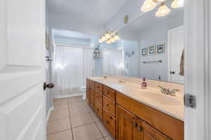 Full bathroom featuring double vanity, curtained shower, tile patterned flooring, and a sink