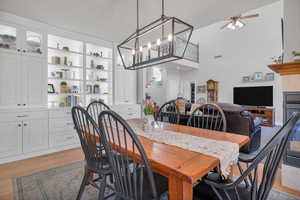 Dining room featuring a towering ceiling, a ceiling fan, visible vents, and light wood-style floors