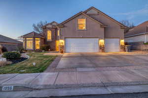 Traditional-style house with stone siding, stucco siding, a garage, and driveway