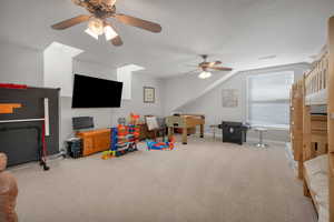 Recreation room featuring a ceiling fan, lofted ceiling, baseboards, carpet flooring, and visible vents
