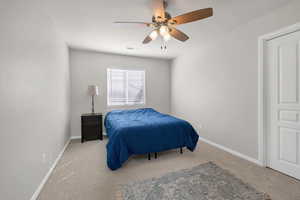 Carpeted bedroom with baseboards, visible vents, and a ceiling fan