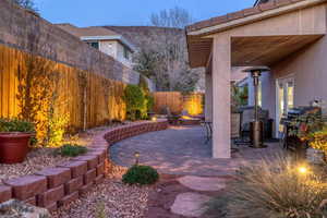 View of patio featuring an outdoor fire pit, area for grilling, and a fenced backyard