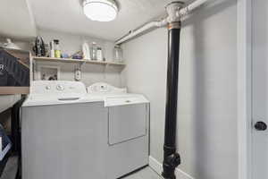 Clothes washing area with laundry area, washer and clothes dryer, and a textured ceiling