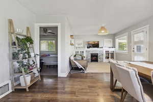 Dining area with a ceiling fan, baseboards, visible vents, wood finished floors, and a fireplace