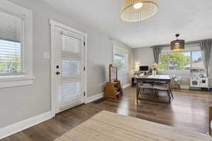 Dining space with a textured ceiling, baseboards, visible vents, and wood finished floors