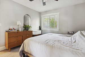 Bedroom with light colored carpet, baseboards, and a ceiling fan