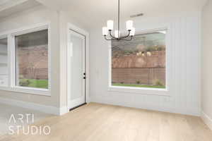 Unfurnished dining area featuring a chandelier, wood finished floors, and baseboards