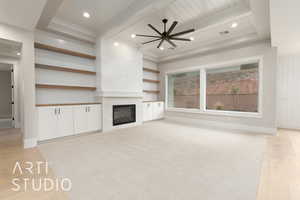 Unfurnished living room featuring a tile fireplace, light wood-type flooring, beam ceiling, baseboards, and a ceiling fan