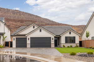 View of front of home with decorative driveway, a garage, a mountain view, stucco siding, and a tiled roof