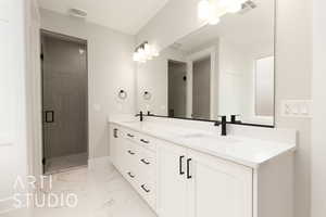 Full bathroom featuring marble look tiles, a shower stall, double vanity, and baseboards