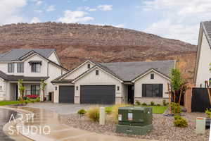 Modern farmhouse featuring an attached garage, a mountain view, decorative driveway, and stucco siding