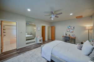 Bedroom with connected bathroom, wood finished floors, a ceiling fan, baseboards, and recessed lighting
