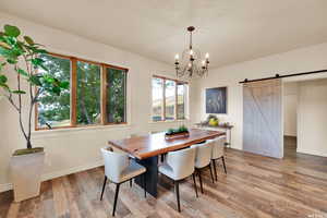 Dining space featuring a barn door, light wood-style flooring, a notable chandelier, and baseboards