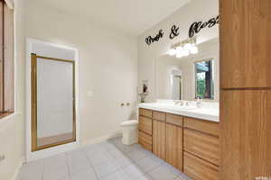 Bathroom featuring toilet, a stall shower, baseboards, tile patterned flooring, and vanity