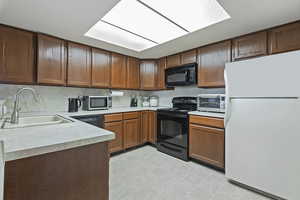 Kitchen featuring a sink, a toaster, black appliances, light countertops, and decorative backsplash
