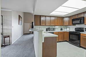 Kitchen featuring a peninsula, a sink, black appliances, light countertops, and tasteful backsplash