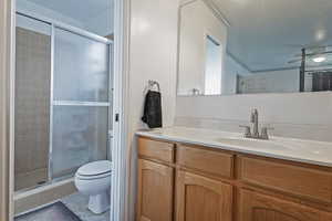 Full bathroom with tile patterned floors, vanity, toilet, and a stall shower